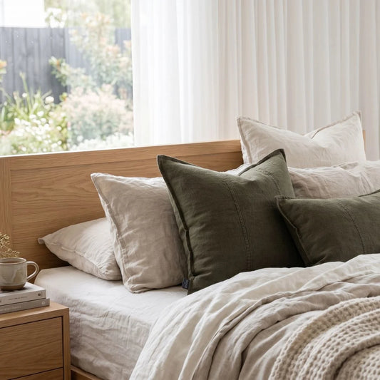 Bedroom with a bed featuring pillows and a wooden headboard, with a window in the background.