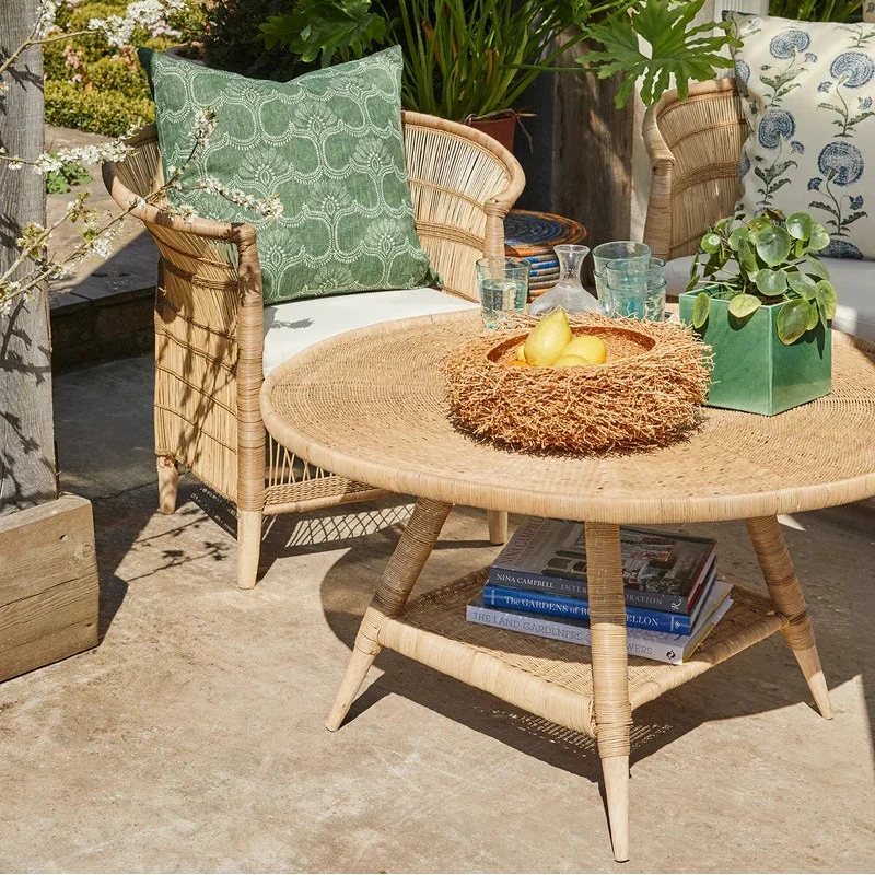 Outdoor seating area with wicker furniture, cushions, and a small table with a candle.