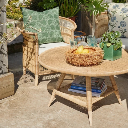 Outdoor seating area with wicker furniture, cushions, and a small table with a candle.