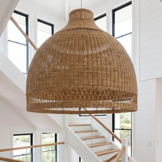 A large woven natural rattan dome pendant light hanging in a bright, modern white staircase hallway with wood floors and glass railings.
