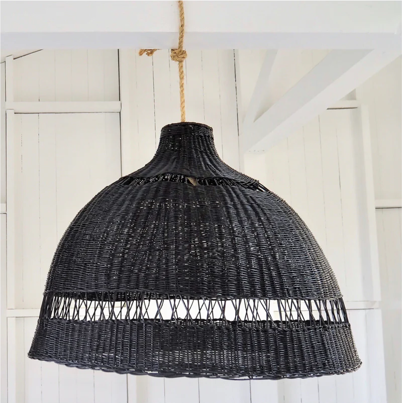 Black wicker pendant light hanging against a white wooden panel background