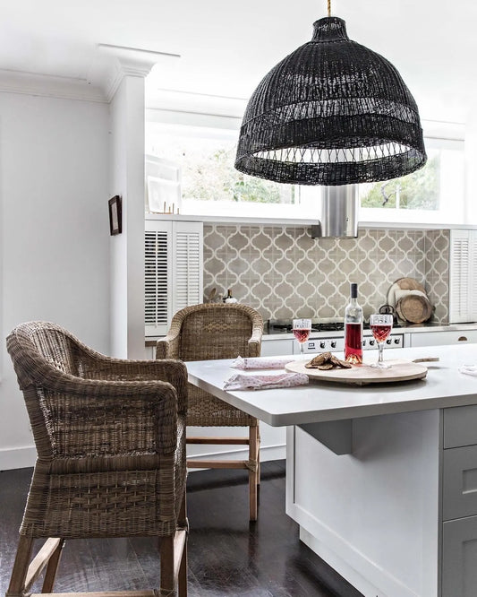 Dining area with wicker chairs, a kitchen island, and a black pendant light.