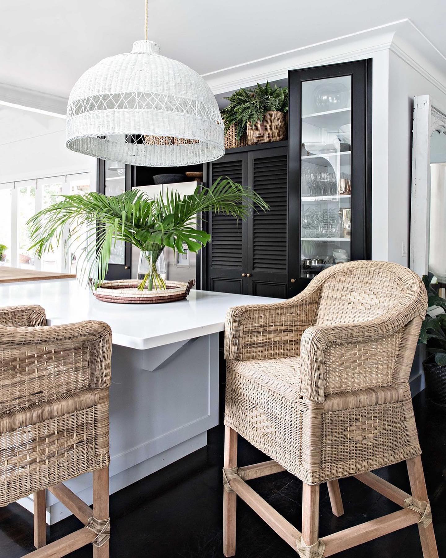 Dining area with wicker chairs, white table, and pendant light in a modern kitchen.