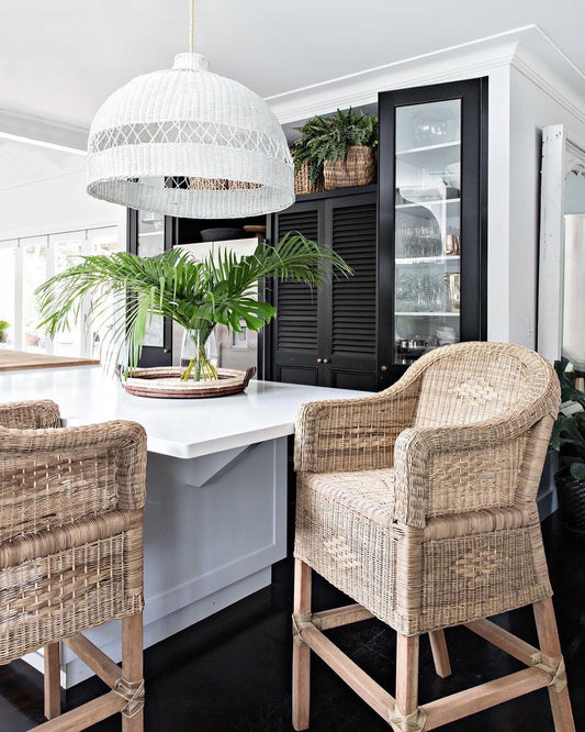 Dining area with wicker chairs, white table, and pendant light in a modern kitchen.