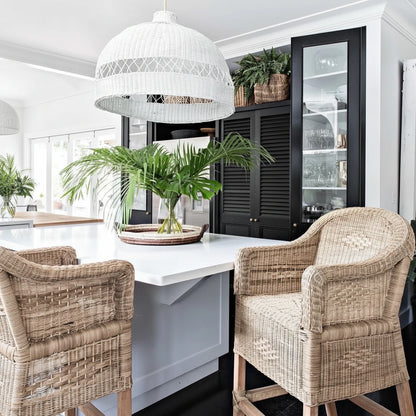 Dining area with wicker chairs, white table, and pendant light in a modern kitchen.
