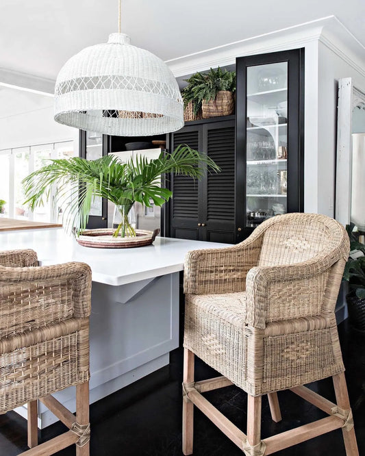 Dining area with wicker chairs, white table, and pendant light in a modern kitchen.