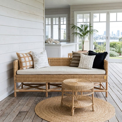 Wicker daybed with cushions on a wooden deck with a view of a city skyline.