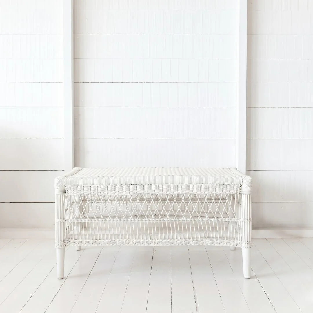 White wicker bench against a white wooden wall