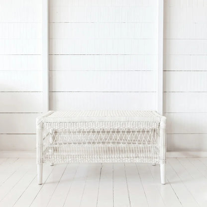 White wicker bench against a white wooden wall