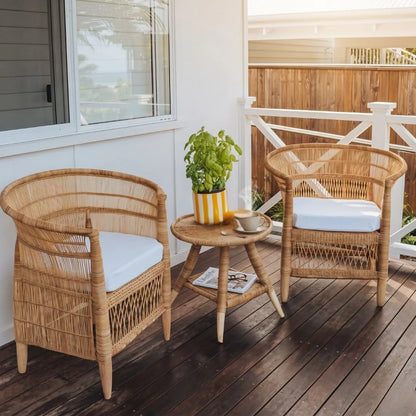 Wicker chairs with cushions and a small table on a wooden deck.