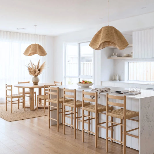Modern kitchen with wooden dining table and chairs, white countertops, and pendant lights.
