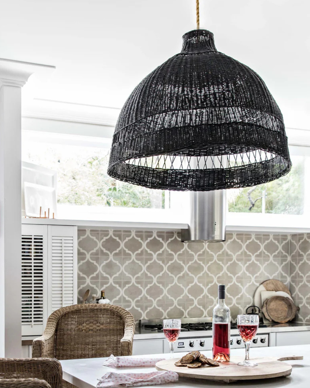 Black woven pendant light hanging in a kitchen with a dining table and chairs.