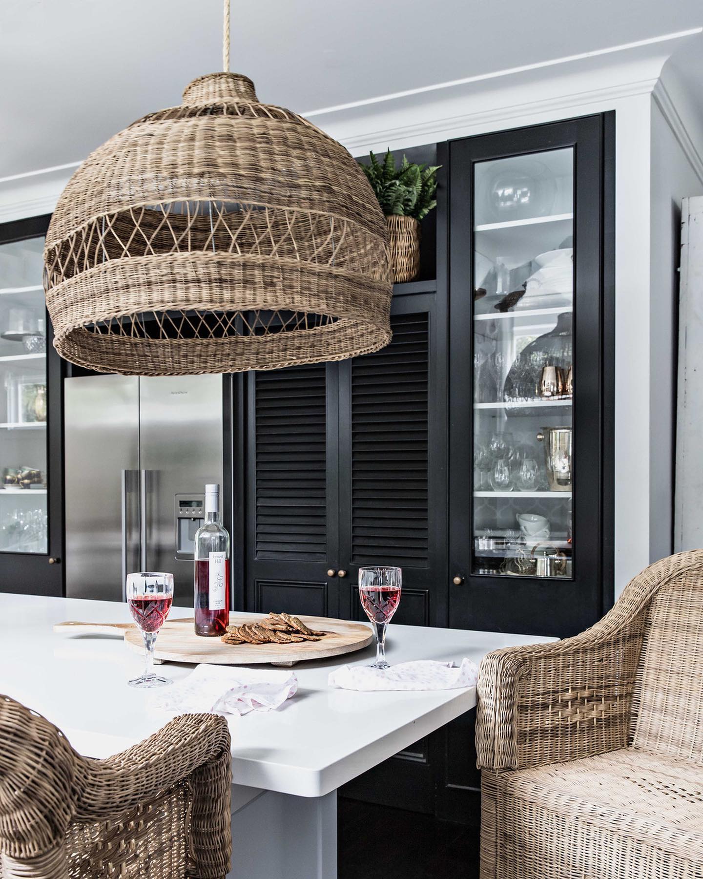 Dining area with wicker chairs and a large woven pendant light in a modern kitchen.