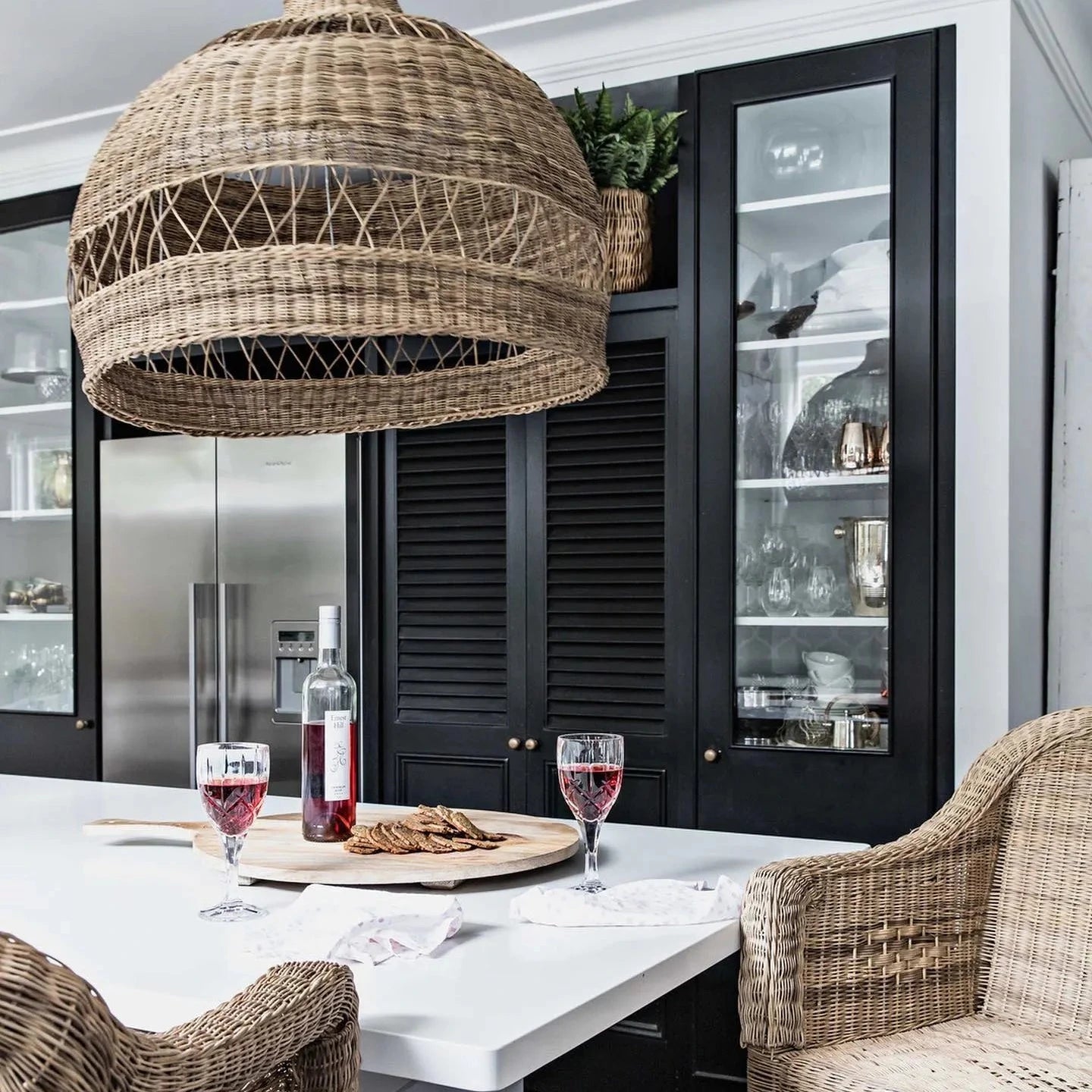 Dining area with wicker chairs and a large woven pendant light in a modern kitchen.