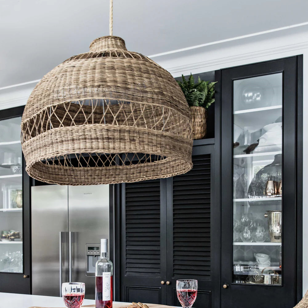 Woven pendant light hanging in a modern kitchen with black cabinets and glassware.