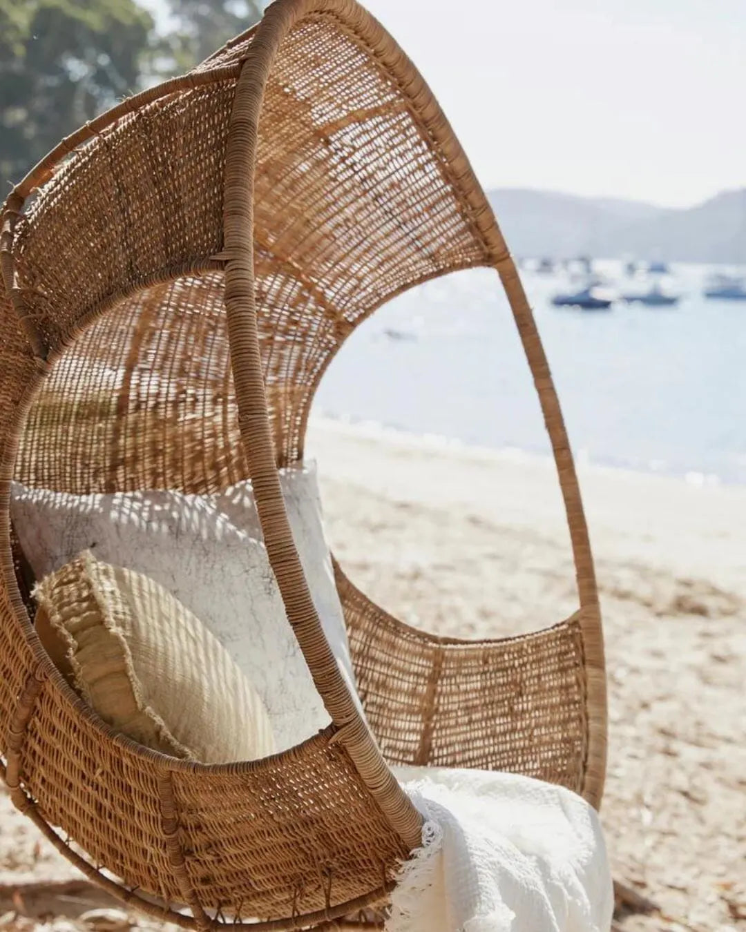 Wicker egg-shaped chair on a beach with ocean view