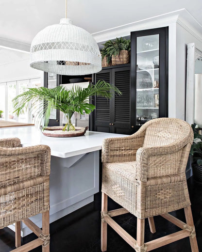 Kitchen area with wicker chairs, white table, and pendant light in a modern kitchen.