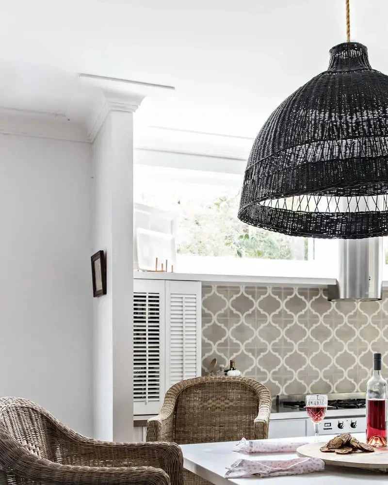 Kitchen with woven cane stools, a white table, and wine glasses.