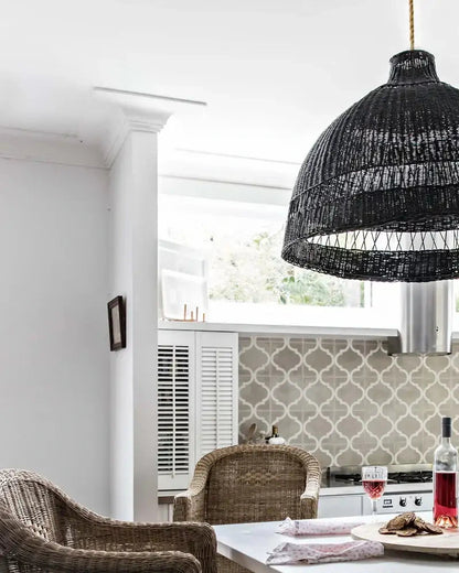 Kitchen with woven cane stools, a white table, and wine glasses.