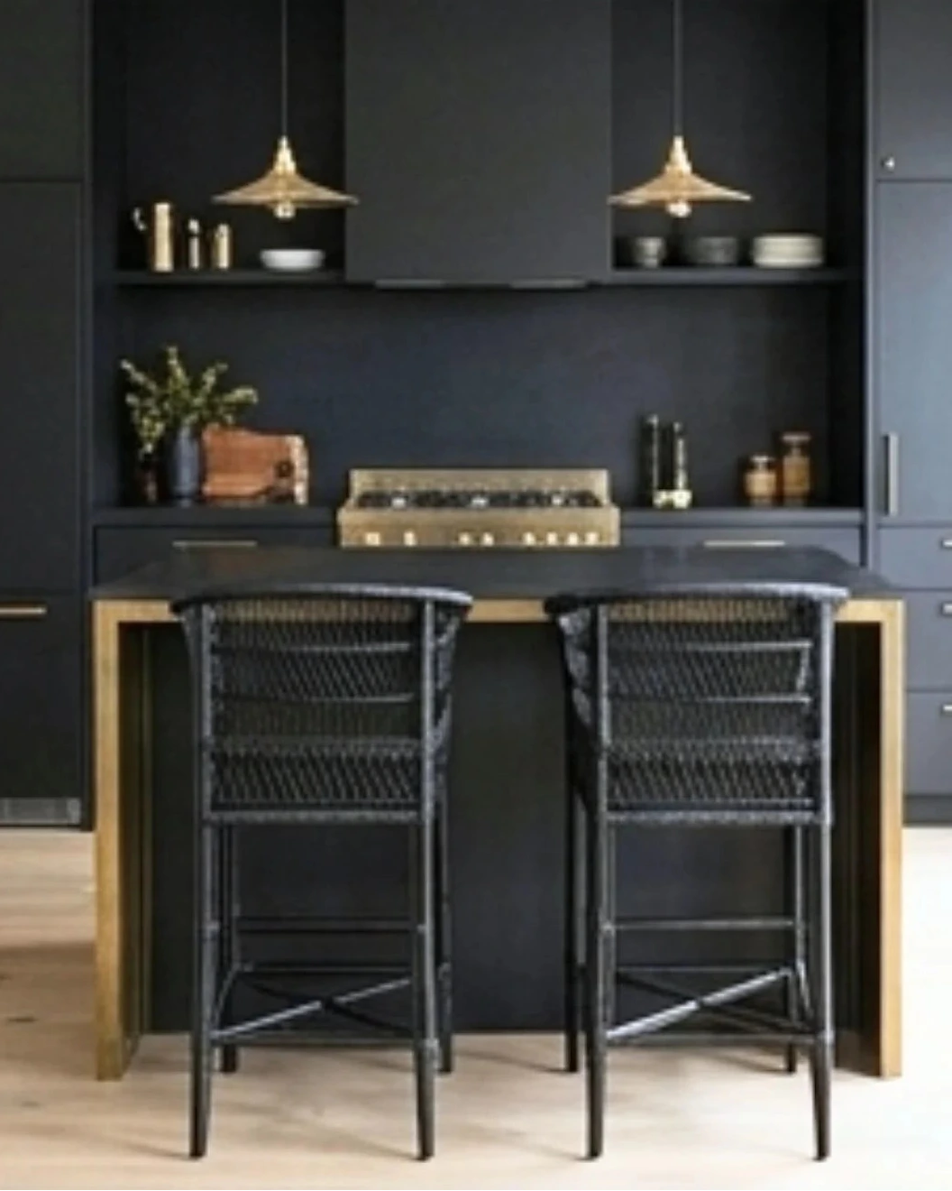 Modern kitchen with dark cabinets, a black island, and wicker bar stools.