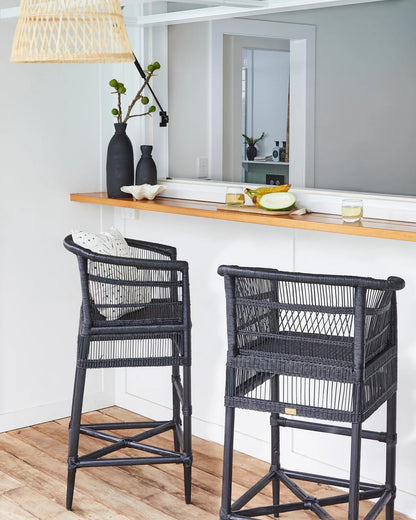 Two black wicker bar stools in a kitchen setting with a wooden counter.