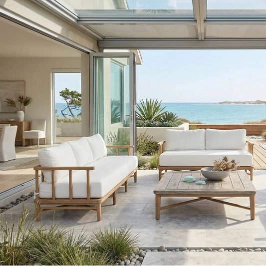 Outdoor patio with white cushioned furniture and a view of the ocean.