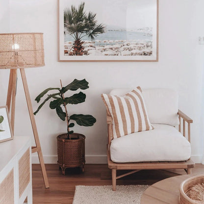 Living room with a wooden armchair, plant, and framed picture of a beach.