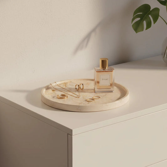 Perfume bottle on a round wooden tray with jewelry on a light surface, plant in the corner.