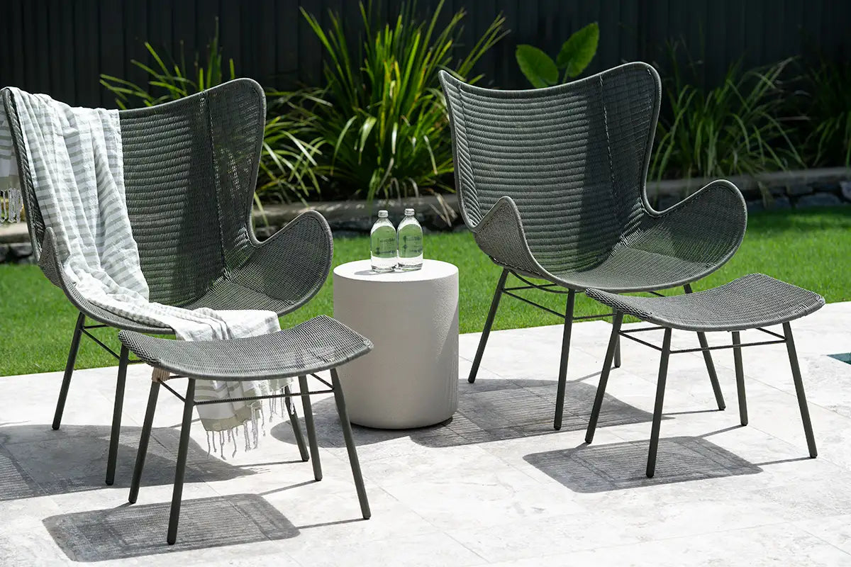 Outdoor furniture set with two chairs, a table, and an ottoman on a patio.
