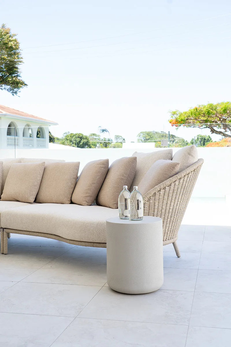 Beige outdoor sofa with cushions on a patio area with a clear sky.