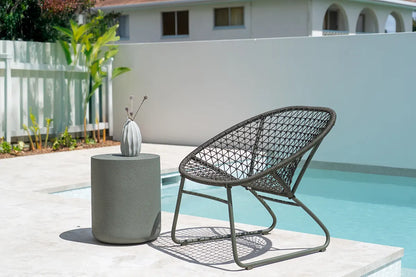 Outdoor chair and table by a poolside with a house in the background
