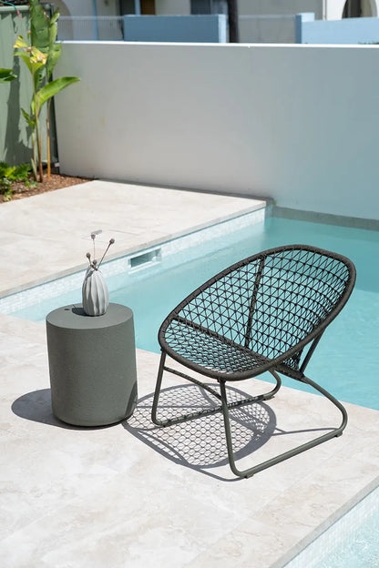 Woven chair and cylindrical table by a poolside
