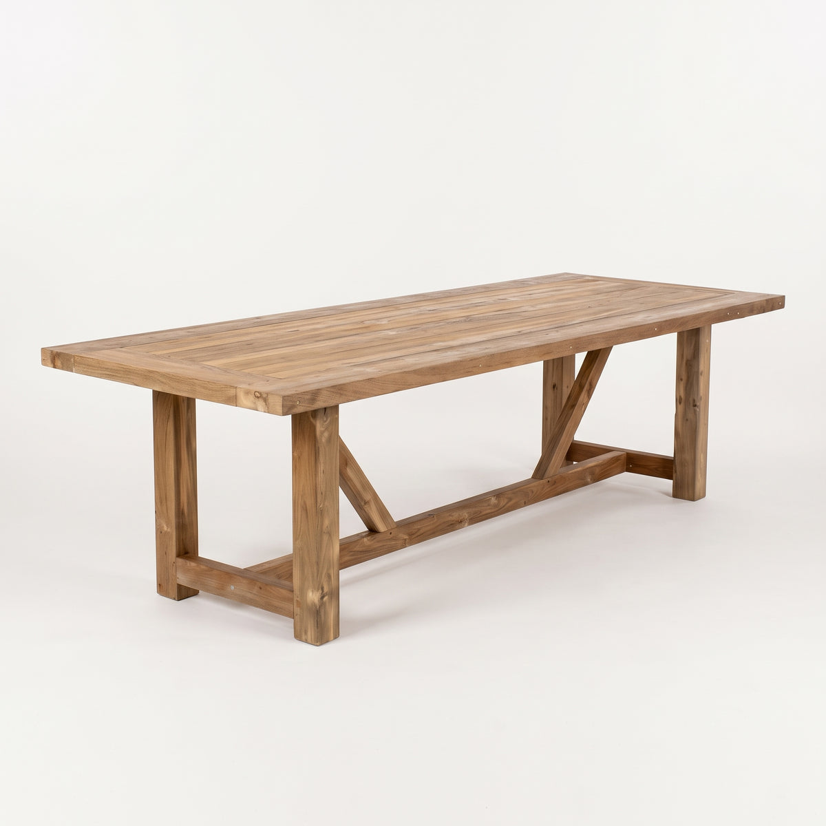 A rustic rectangular wooden dining table with a natural brown finish and X-brace support legs, photographed on a seamless white studio background.