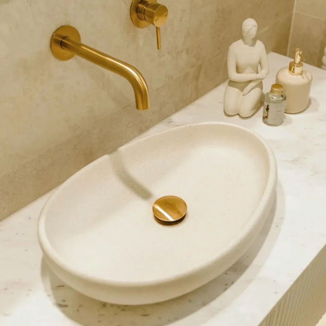 Bathroom sink with gold faucet and decorative items on a countertop.