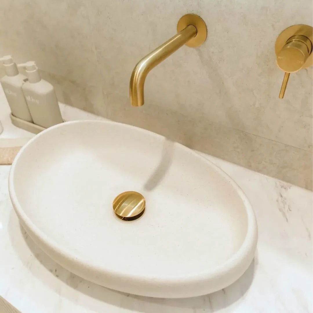 White sink with gold faucet and handles in a bathroom setting