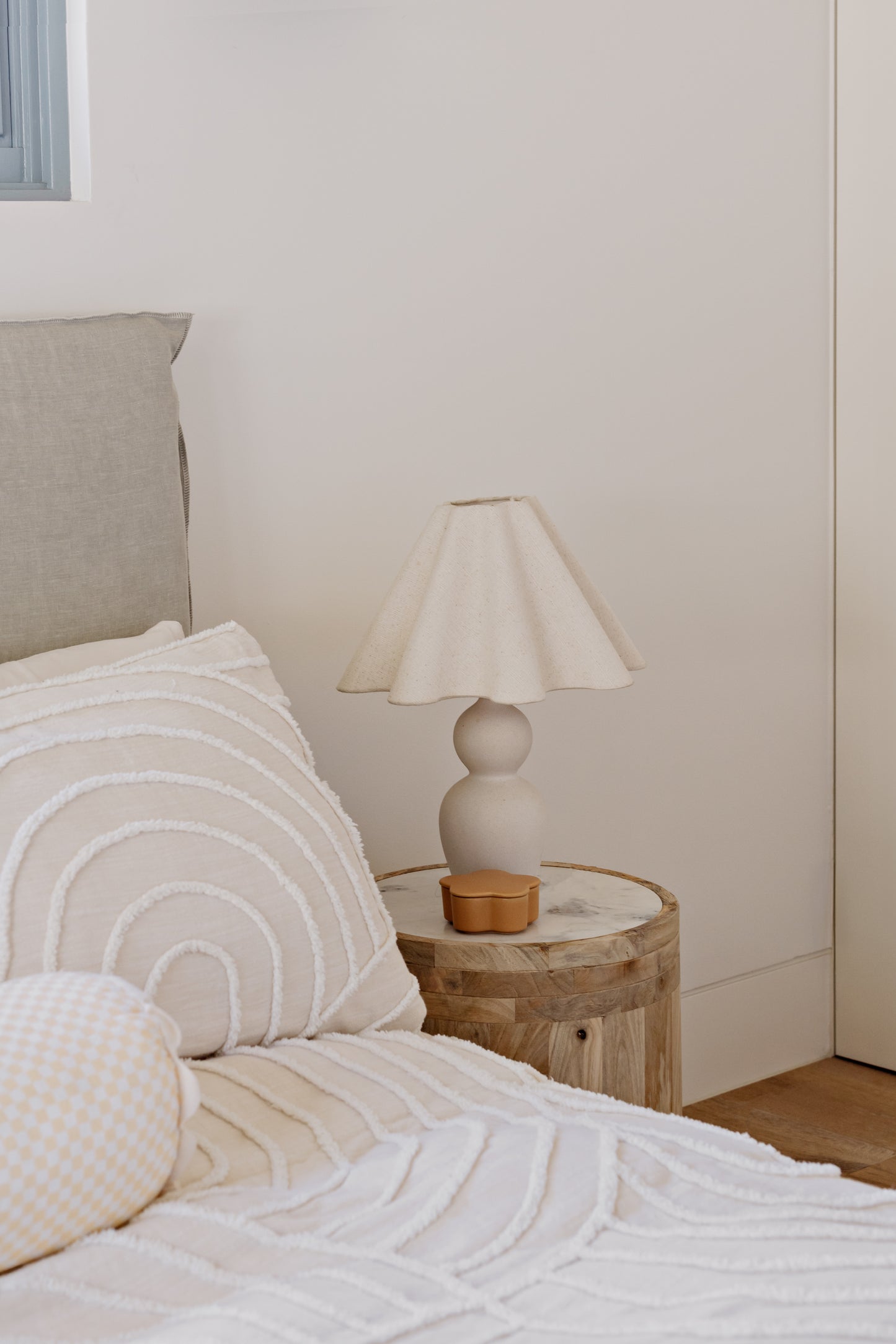 Bedroom with a bed featuring pillows and a wooden side table with a lamp.
