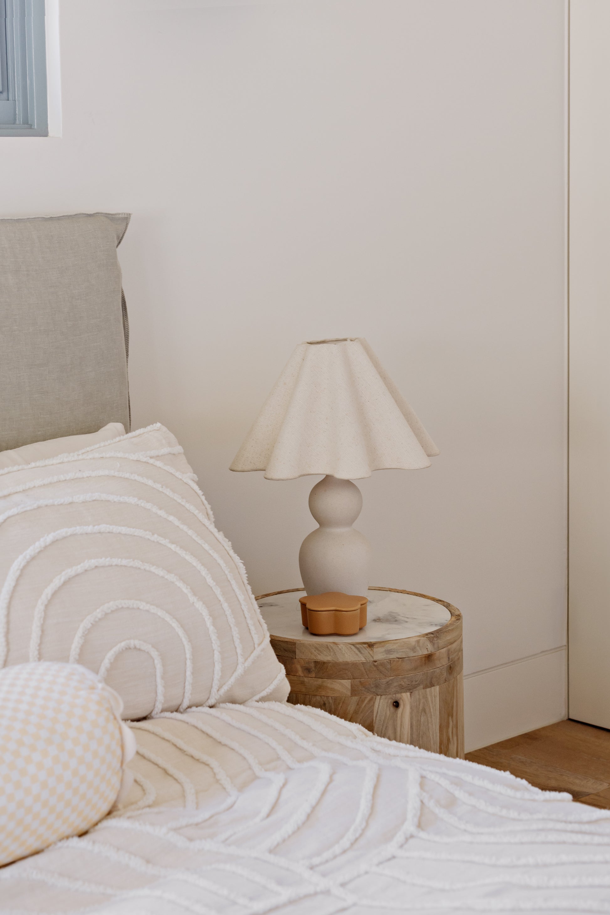 Bedroom with a bed featuring pillows and a wooden side table with a lamp.