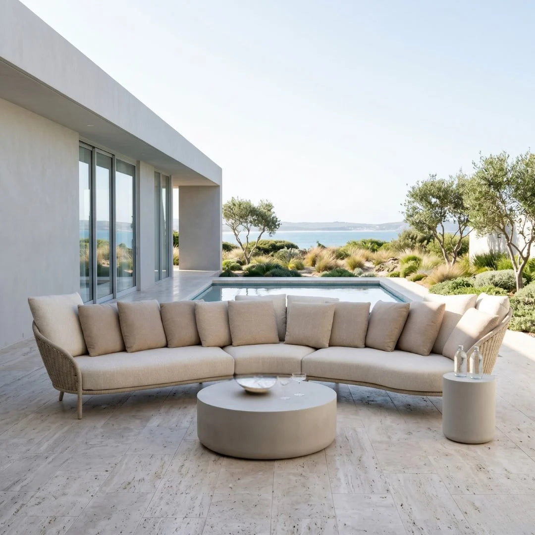 Modern outdoor furniture set with beige cushions on a patio with ocean view