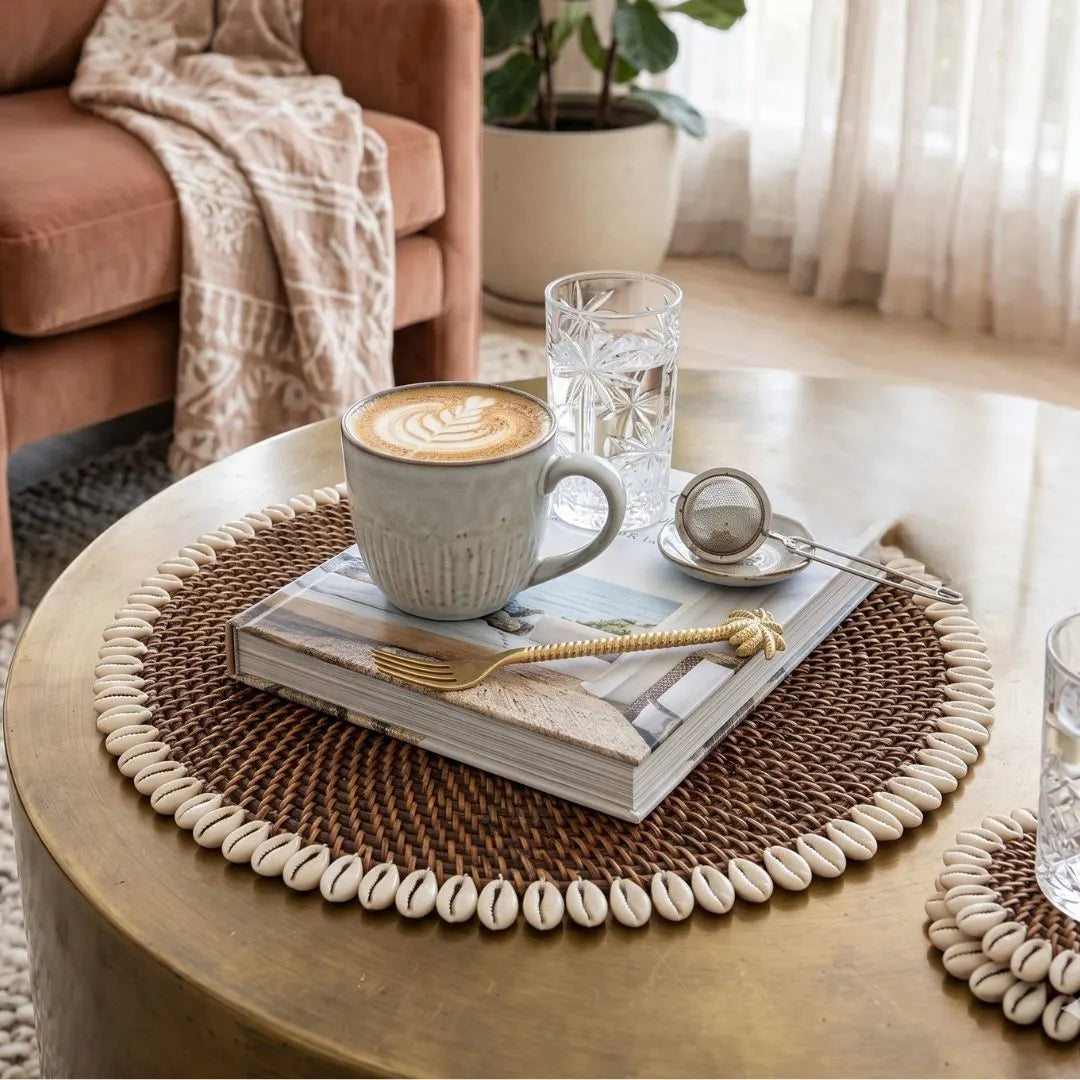 Café setting with a cup of coffee, glass of water, and book on a round wooden table.