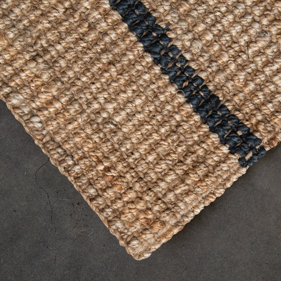 Close-up of a textured beige carpet corner with a dark border on a dark surface.