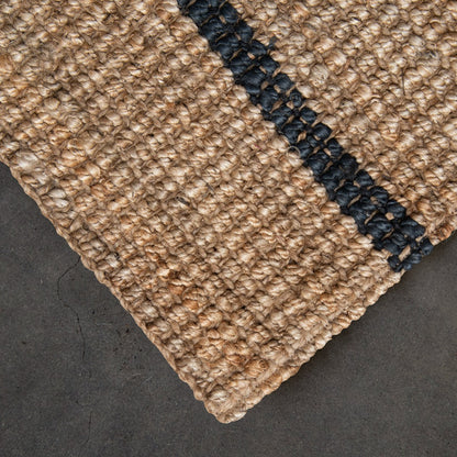 Close-up of a textured beige carpet corner with a dark border on a dark surface.
