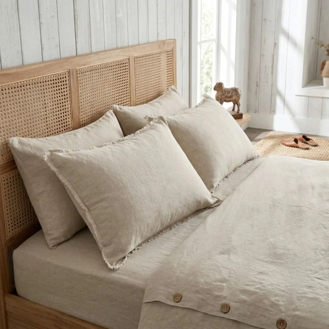 Beige bedding set on a bed with a wooden headboard in a bright room.