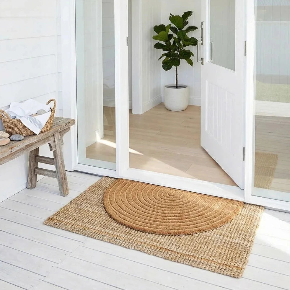 Round woven mat on a wooden deck with a sliding glass door in the background.