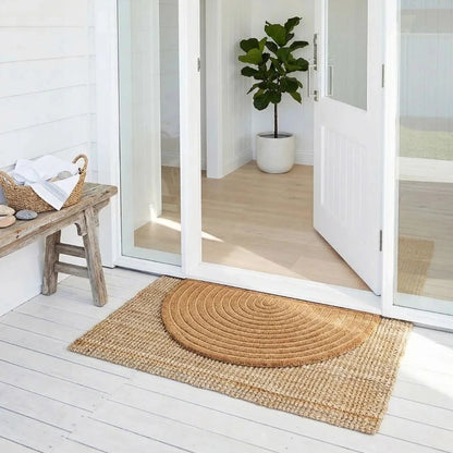 Round woven mat on a wooden deck with a sliding glass door in the background.