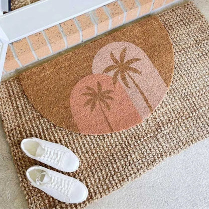 Doormat with palm tree design on a brick surface, with white sneakers in front.