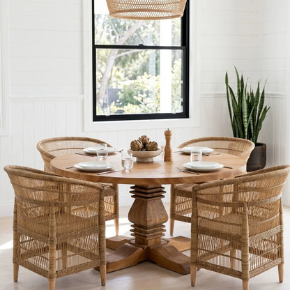 Dining room with wooden table and wicker chairs near a window.