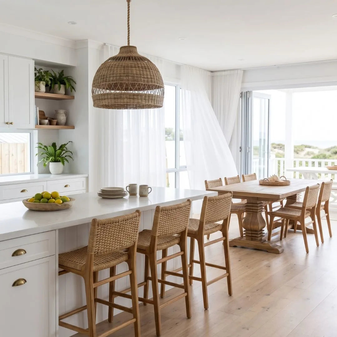 Modern kitchen with white island, wooden chairs, and large windows.