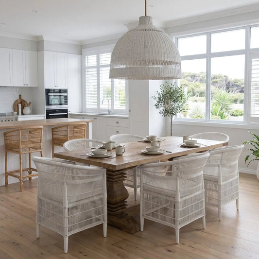 Dining area with wooden table and wicker chairs in a bright kitchen.