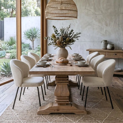 Dining room with wooden table and chairs, set for a meal with a vase of flowers and bread.