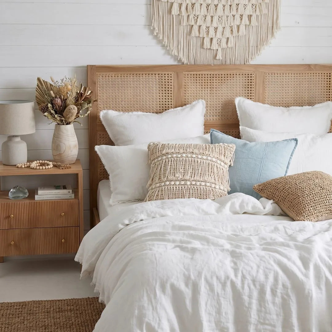 Bedroom with a wooden headboard and white bedding, featuring decorative pillows and a nightstand.